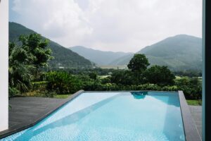 Stunning villa with an infinity pool overlooking lush green mountains and a serene landscape.